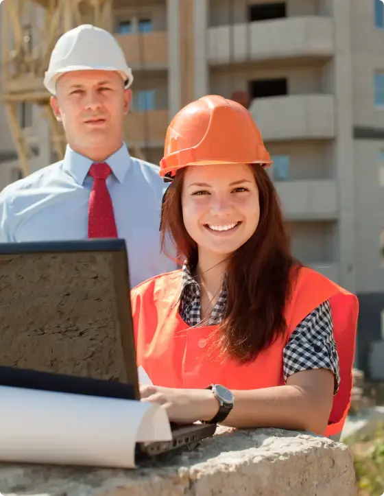 Foreman in hard hat and red tie behind a worker in orange hi-vis holding a laptop — general liability coverage