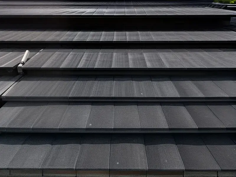 Perspective view of a dark grey standing-seam metal roof in late afternoon light — Hawaii roofing contractor insurance