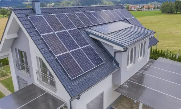 Aerial view of a modern white home with rooftop solar panels on a grey roof, green lawn — Arkansas roofing contractor insurance